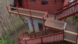 A red log cabin with a balcony and a staircase. - Bear Necessities: peaceful, With/romantic hot tub. (Sevierville)