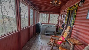 A covered porch with wooden rocking chairs, a ceiling fan, and a view of trees. - Bear Necessities: peaceful, With/romantic hot tub. (Sevierville)