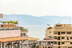 Un hôtel en bord de mer doté de nombreux balcons donnant sur l’océan, offrant une vue dégagée sur la mer et s’inscrivant dans un paysage montagneux.