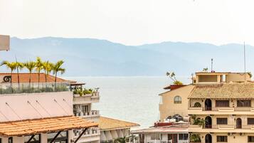 Un edificio costero con balcones que dan al mar, con una vista despejada del agua y montañas a lo lejos.