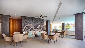 Ein moderner Lounge-Bereich mit Sitzgelegenheiten, darunter Sofas und Sessel, und einem Deckenventilator.