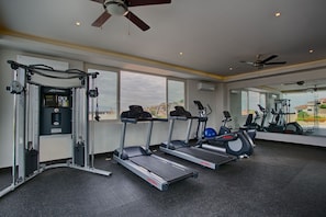 A gym with treadmills, a weight machine, and a mirror wall reflecting the city view. - Top-Floor Penthouse · Walk to Beach · King Bed (Puerto Vallarta)