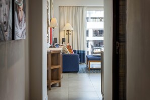 A hotel room with a desk, two lamps, a sofa, a chair, and a view of the outside. - Top-Floor Penthouse · Walk to Beach · King Bed (Puerto Vallarta)