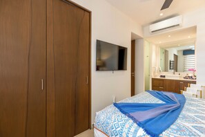 A bedroom with a large wardrobe, a bed with patterned bedding, a flat-screen TV, and a bathroom with a mirror and sink. - Top-Floor Penthouse · Walk to Beach · King Bed (Puerto Vallarta)
