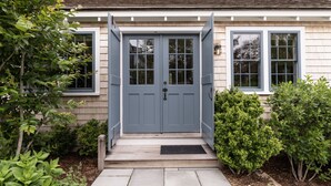 A house with a grey front door, two windows, and a small porch.