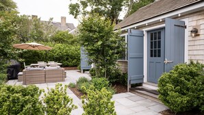 A patio with outdoor furniture, a door, and a small garden area.