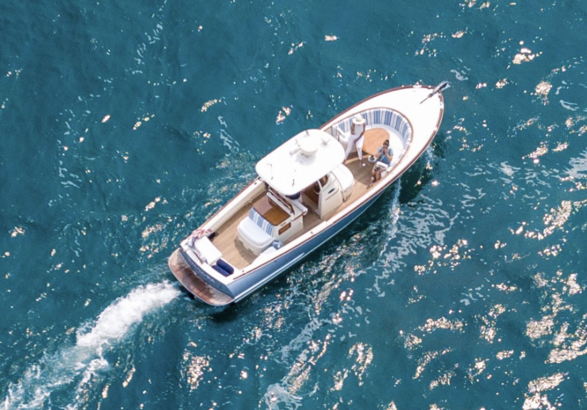 Ein kleines Motorboot mit Kabine und Sitzgelegenheiten fährt auf dem Wasser.