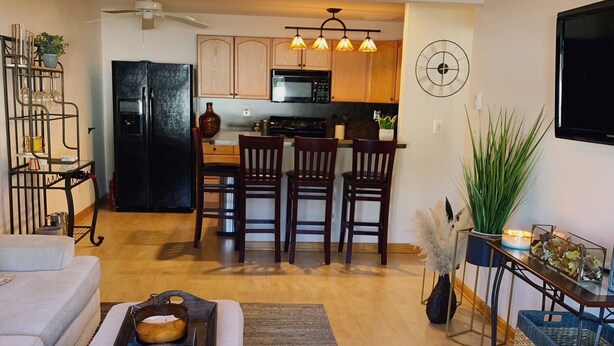 A modern living room with a sofa, a coffee table, and a dining area with chairs and a kitchen in the background.
