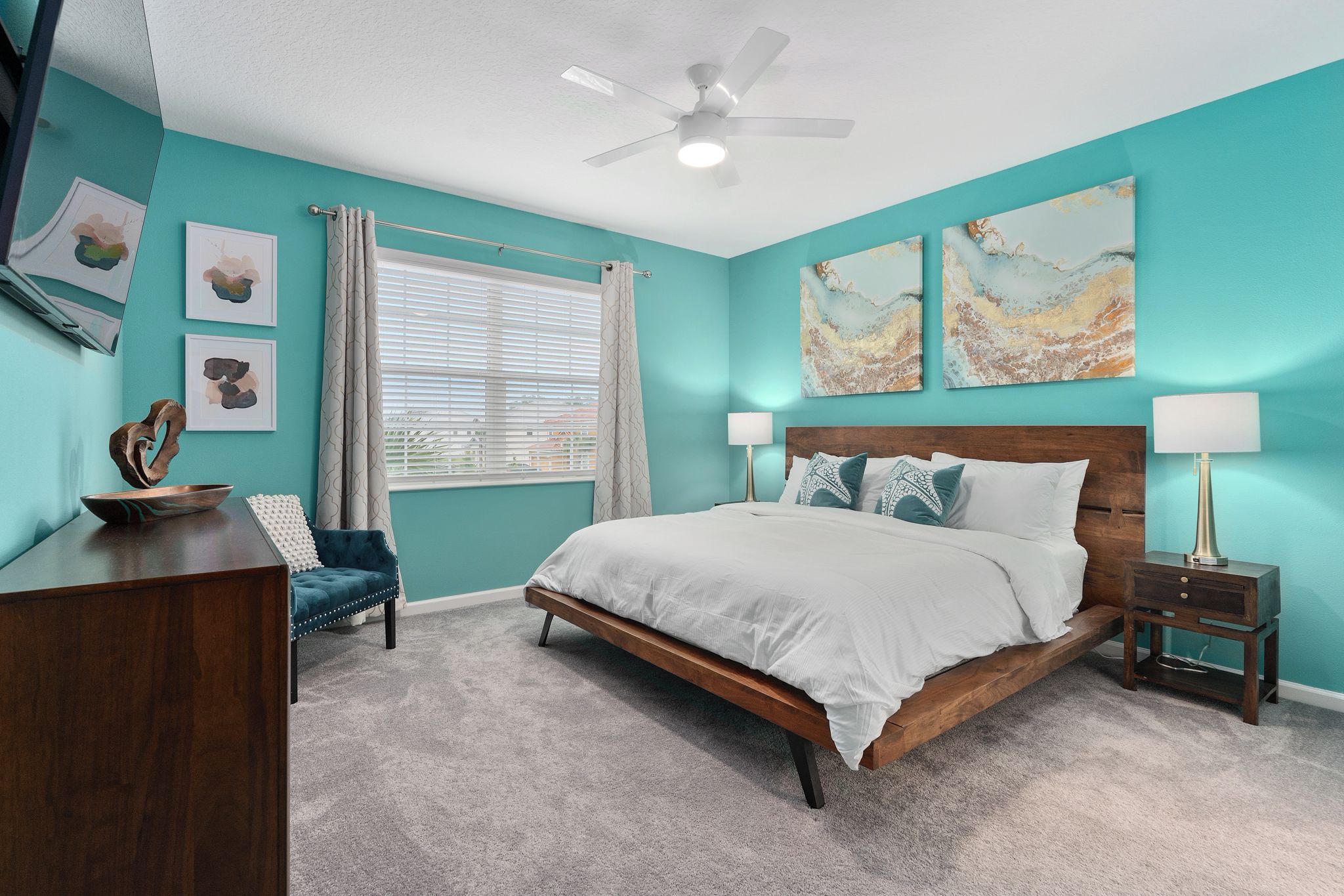A bedroom with teal walls, a wooden bed, a desk, and a chair.