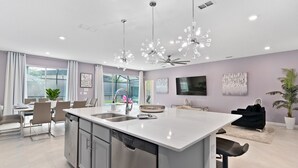A modern kitchen with a central island, stainless steel appliances, and pendant lighting. - Lux Disney Villa | Pool, Theater/games | Sleeps 22 (Kissimmee)