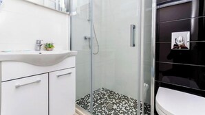 A bathroom with a glass shower enclosure, a white sink, and a black tiled floor. - All Saints Suites B&b Kastela - Double Room (Kaštel Štafilić)
