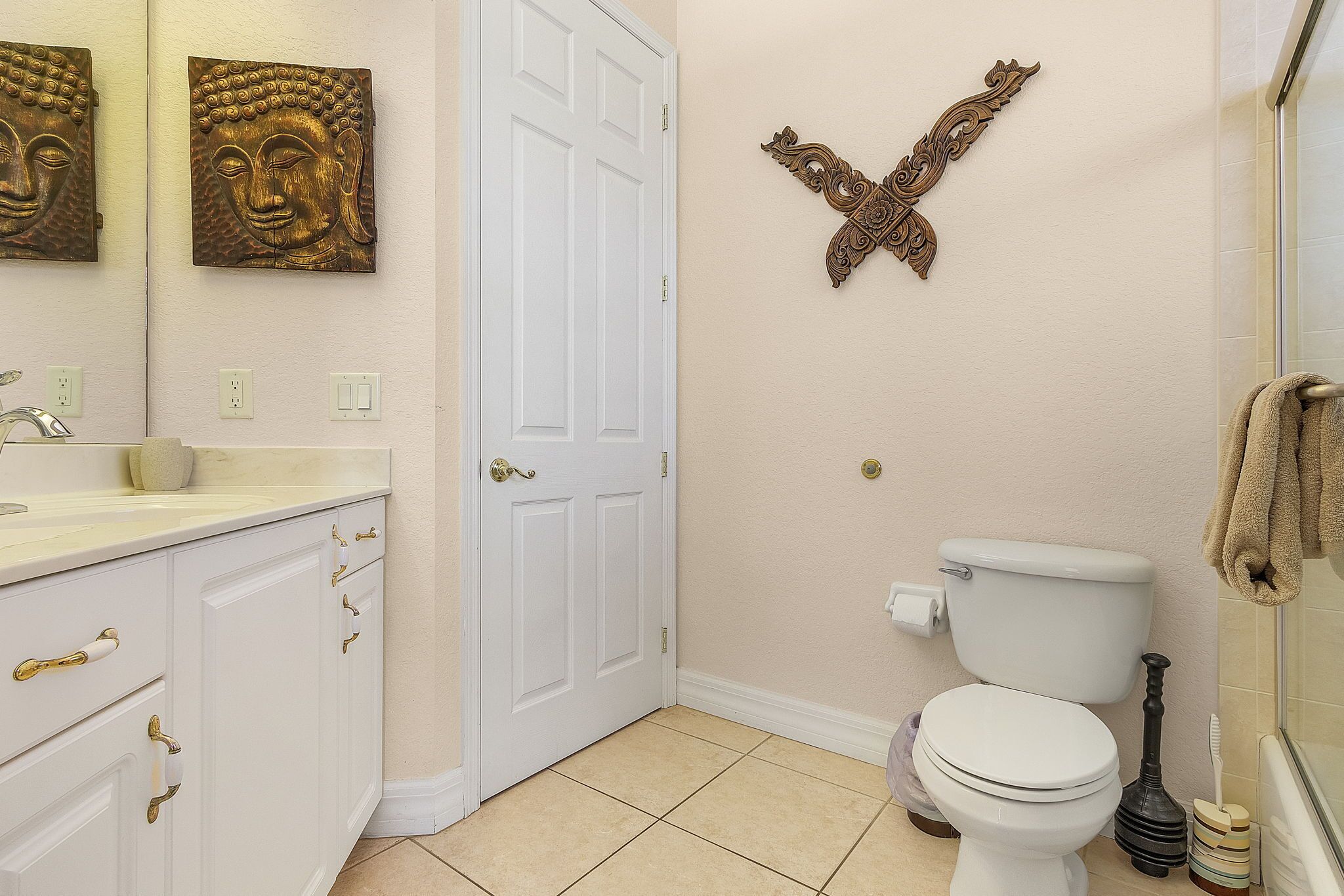 Un baño con inodoro blanco, lavamanos con espejo y decoración en las paredes.