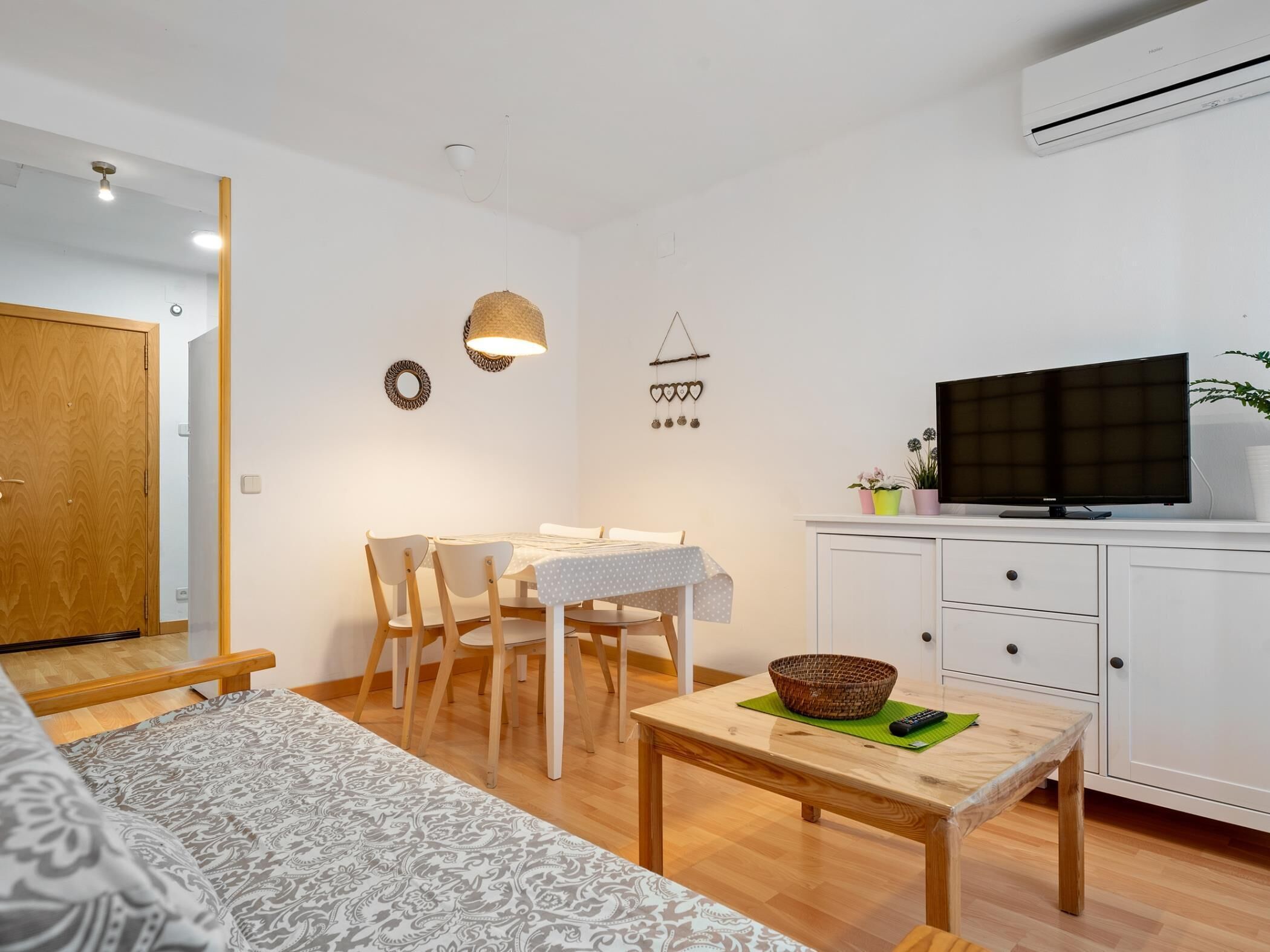 A modern living room with a sofa, dining table, chairs, a TV, and a white cabinet.