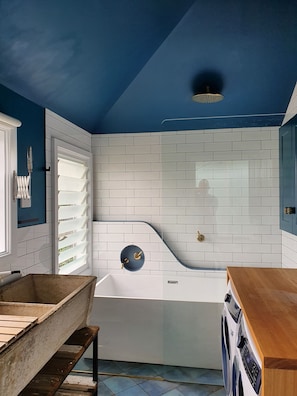 Bathroom features a white bathtub with a curved design and a wooden bench.