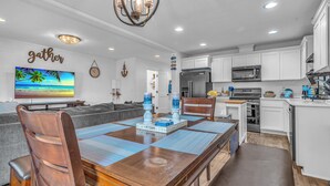 A modern kitchen with white cabinets, a stainless steel refrigerator, and a microwave. - Seaside Riverfront Escape • HotTub • Walk to Beach (Seaside)