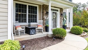 A house with a covered porch, two rocking chairs, a small table, and a potted plant.
