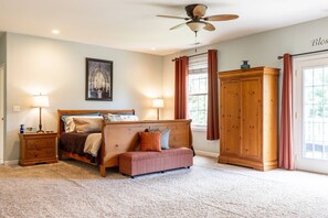 A bedroom with a bed, bedside tables, a bench, a wardrobe, and a ceiling fan.