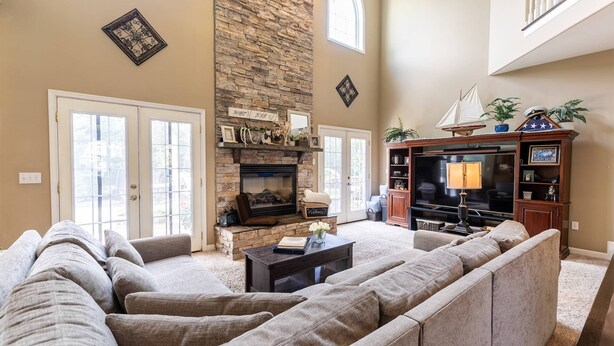 A spacious living room with a stone fireplace, a large TV, and a comfortable seating area.