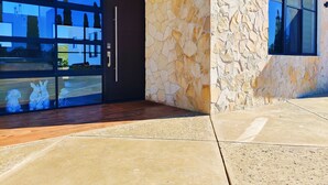 Une entrée moderne avec une façade en pierre, de grandes portes vitrées et un plancher en bois.