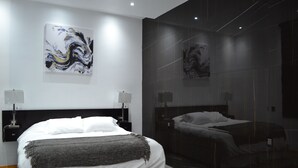 Une chambre d’hôtel moderne avec un grand lit, un lit plus petit et un grand tableau abstrait accroché au mur.