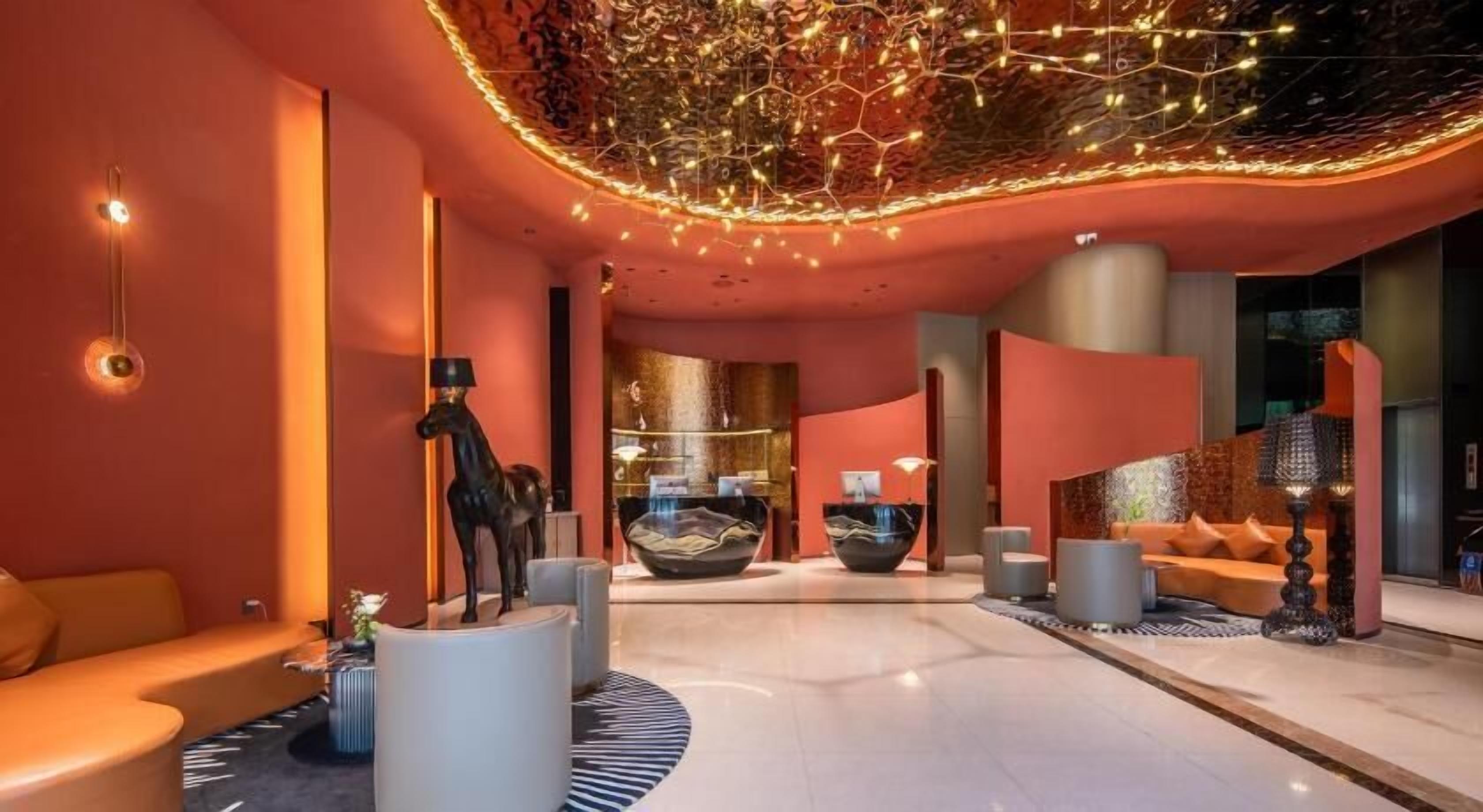 Una hall moderna con un'area salotto centrale, una reception e un design di soffitto originale.