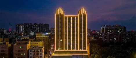 A high-rise building with vertical light strips and a modern design, surrounded by other buildings in a cityscape.