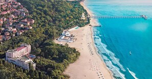 Ovenfra set kystområde med strand, mole og et hotelkompleks.