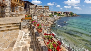 A stone building with a wooden balcony overlooking a clear blue sea. - Room-elite Apartments is Located in the (Pomorie)