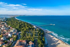 Oversigtsbillede af en kystby med strand, tæt bebygget område og en mole, der strækker sig ud i havet.