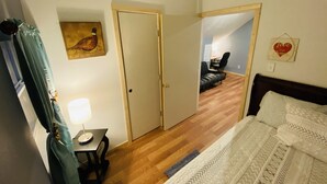 Une chambre à coucher avec un lit, un bureau avec une lampe, une porte, un miroir et un mur orné d’un décor en forme de cœur.