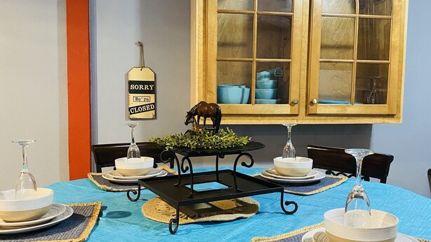 Une table à manger est dressée avec de l’assiette blanche, des bols et un plateau noir sur lequel est posée une plante. Une pancarte indique : « DÉSOLÉ, nous sommes fermés. »