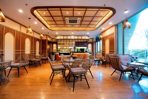 A spacious indoor area with a central bar, wicker furniture, and a high ceiling with a unique design. - Le Palmier Ho Tram Resort (Ho Chi Minh City)