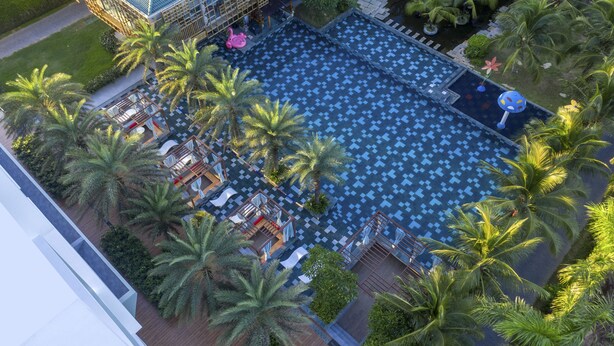 An aerial view of a hotel with a large pool surrounded by palm trees and lounge chairs. - Le Palmier Ho Tram Resort (Ho Chi Minh City)