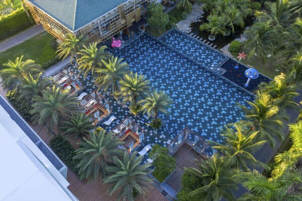 Vista aèria d'un hotel amb una gran piscina envoltada de palmeres i gandules.