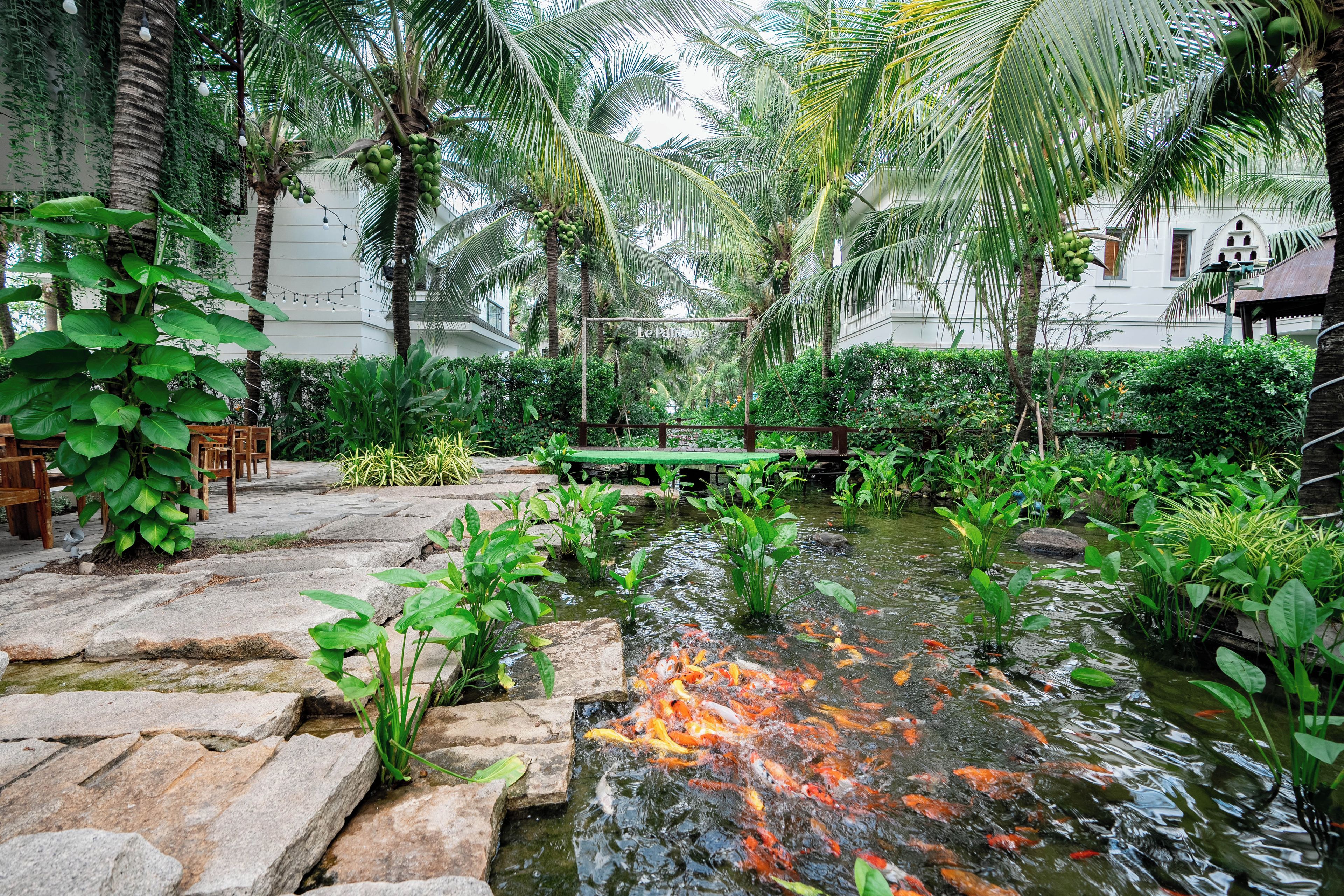 A serene garden with a pond, lush greenery, and a wooden deck.
