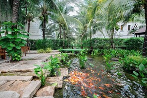 A serene garden with a pond, lush greenery, and a wooden deck. - Le Palmier Ho Tram Resort (Ho Chi Minh City)