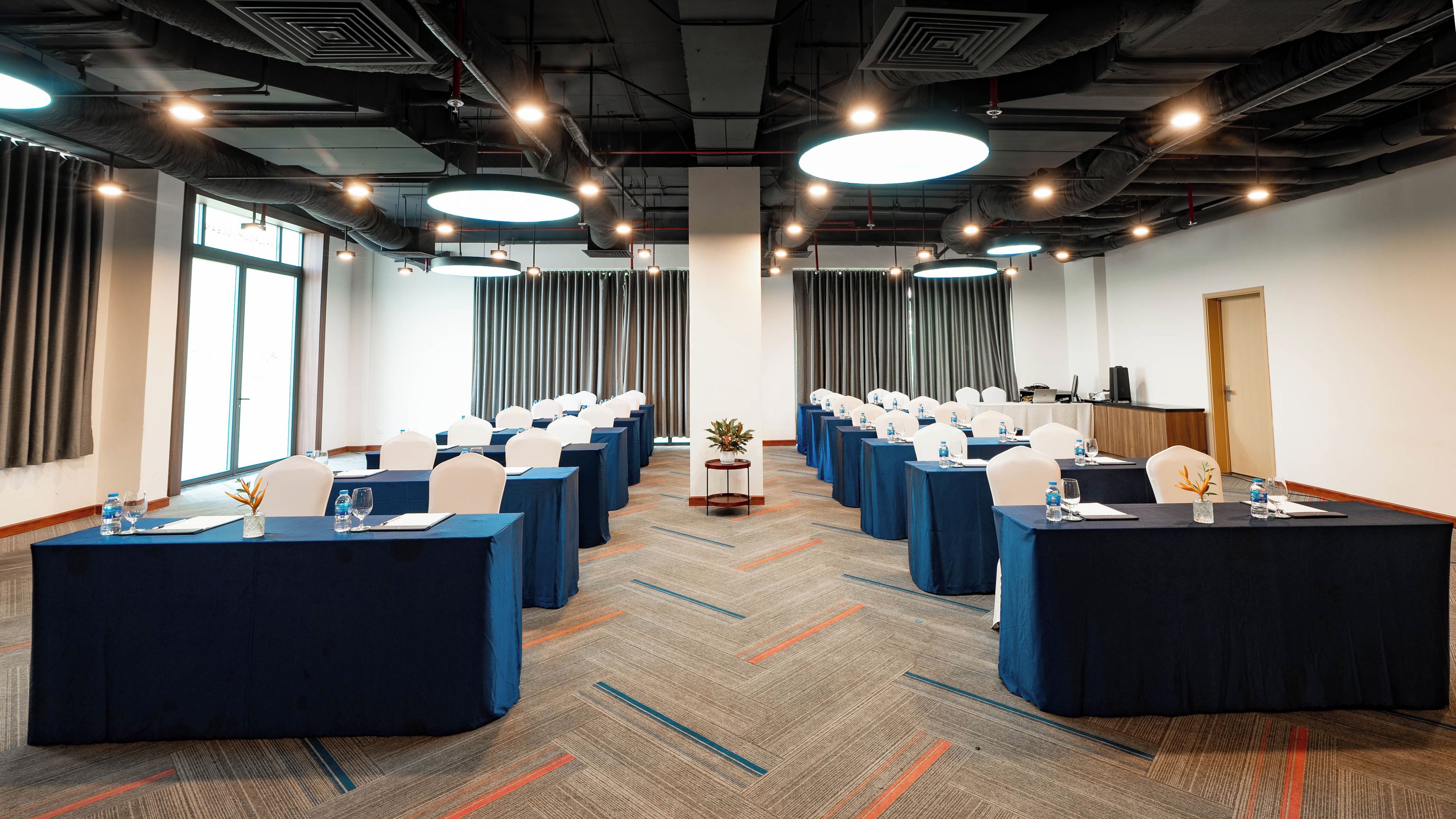 A conference room with rows of tables, chairs, and a podium.