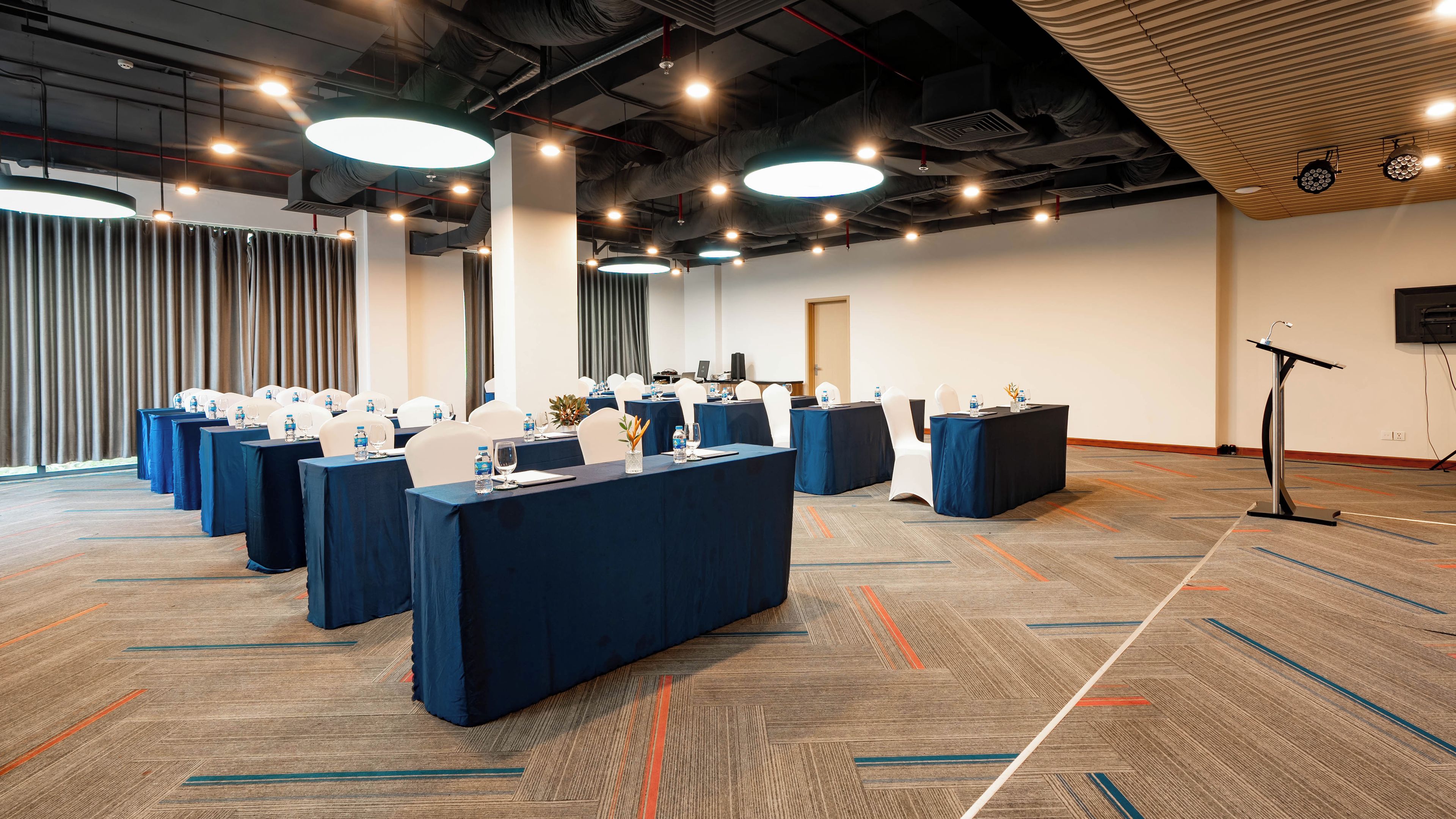 A conference room with multiple tables, chairs, and a podium.