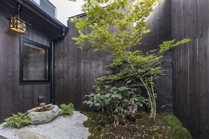 Stroll through a peaceful garden with a tree, stone lantern, and a winding gravel path.