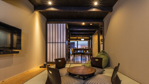 A traditional Japanese-style room with tatami flooring, low wooden tables, and cushions.