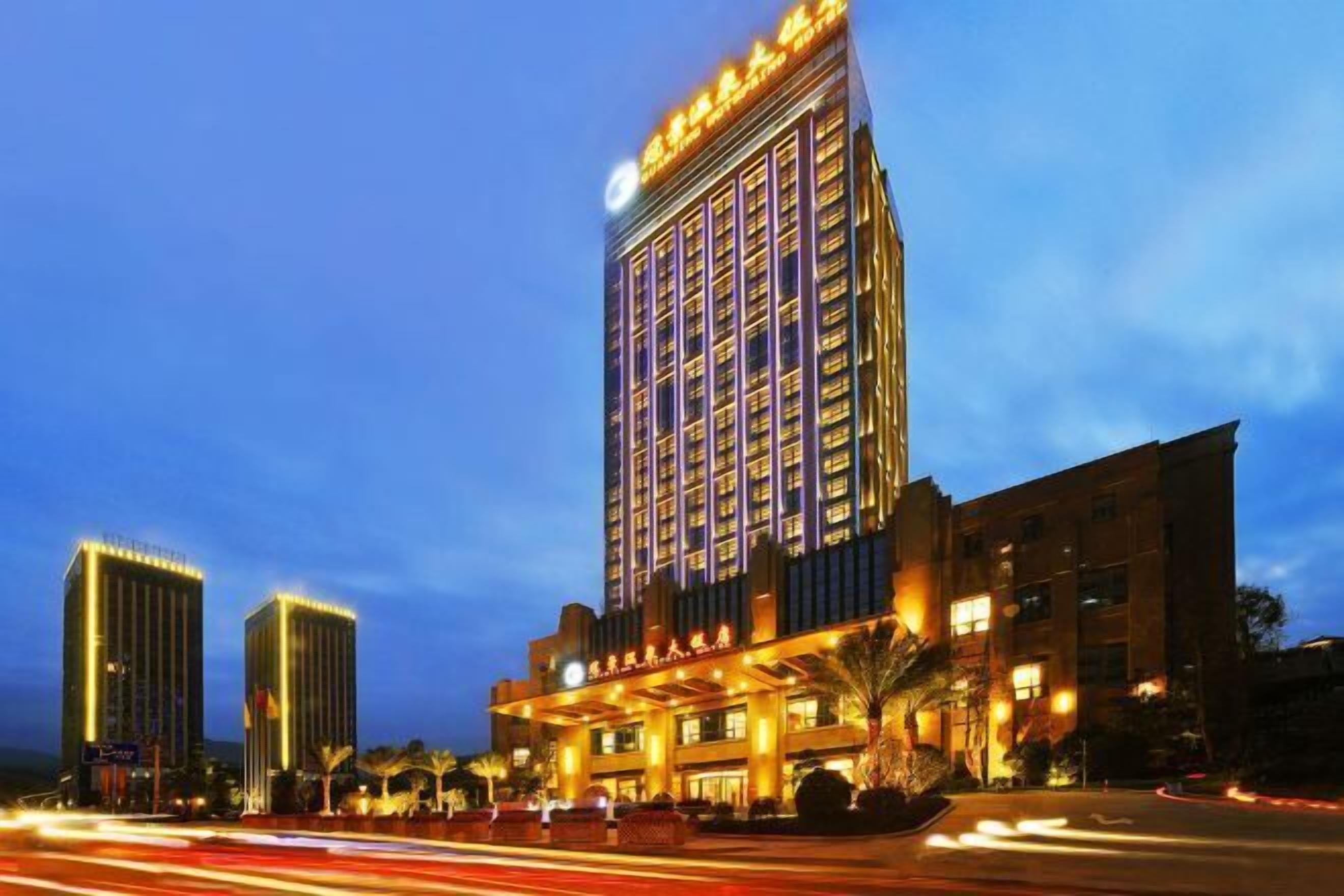 A multi-story hotel with a prominent entrance and a large illuminated sign.