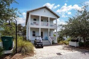 Une maison à deux étages avec un balcon au deuxième étage, une allée et un véhicule de golf garé devant.