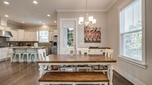 Una cocina moderna con una mesa de comedor de madera, armarios blancos y una araña.