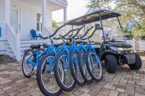 Una hilera de bicicletas azules estacionadas frente a una casa blanca con porche.