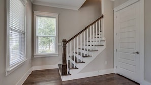 A staircase with wooden steps and white railings leading to a white door.