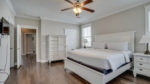 Une chambre à coucher avec un grand lit, un ventilateur de plafond, une commode et une table de chevet.