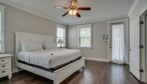 A bedroom with a bed, a nightstand, a ceiling fan, and a door.