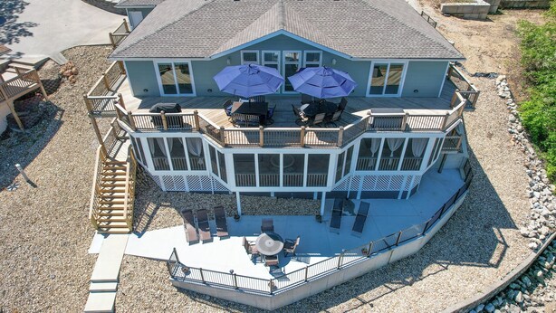 Une grande maison dotée d’une terrasse couverte et de nombreuses fenêtres.