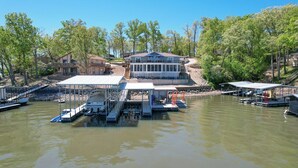 Une propriété au bord du lac, dotée d’un quai, de bateaux et d’une grande maison avec une terrasse offrant une vue sur l’eau.