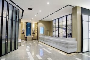 A modern reception area with a marble reception desk, glass partitions, and framed artwork on the walls. - Atour Hotel Manduhai Hohhot (Hohhot)